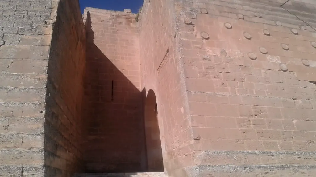 الوجه المائل تحت السور، وفوقه حجرٌ منحوت ذو نتوءات