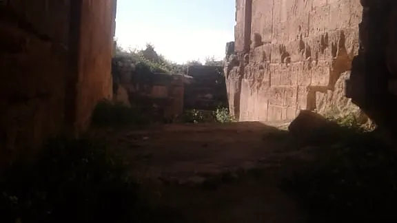 شقٌّ في طريق الدخول، جانباه صخرٌ وبناء